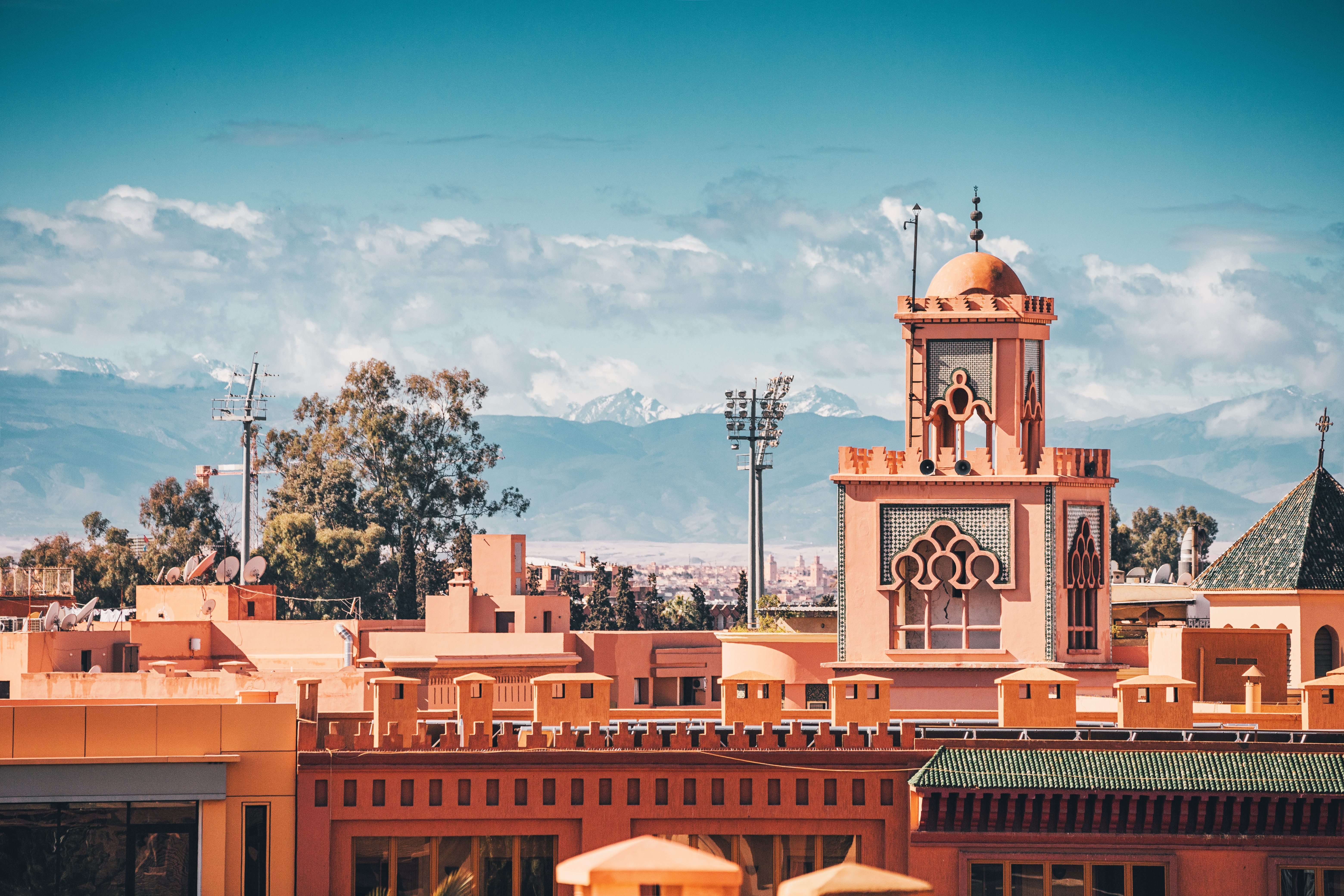 Traditional Moroccan architecture with a minaret and Atlas Mountains rising in the background in Marrakech, Morocco. Photo: Shutterstock